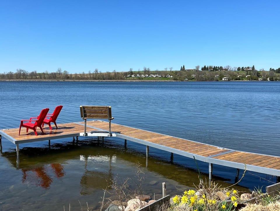 Red Muskoka chairs at the end of the private dock
