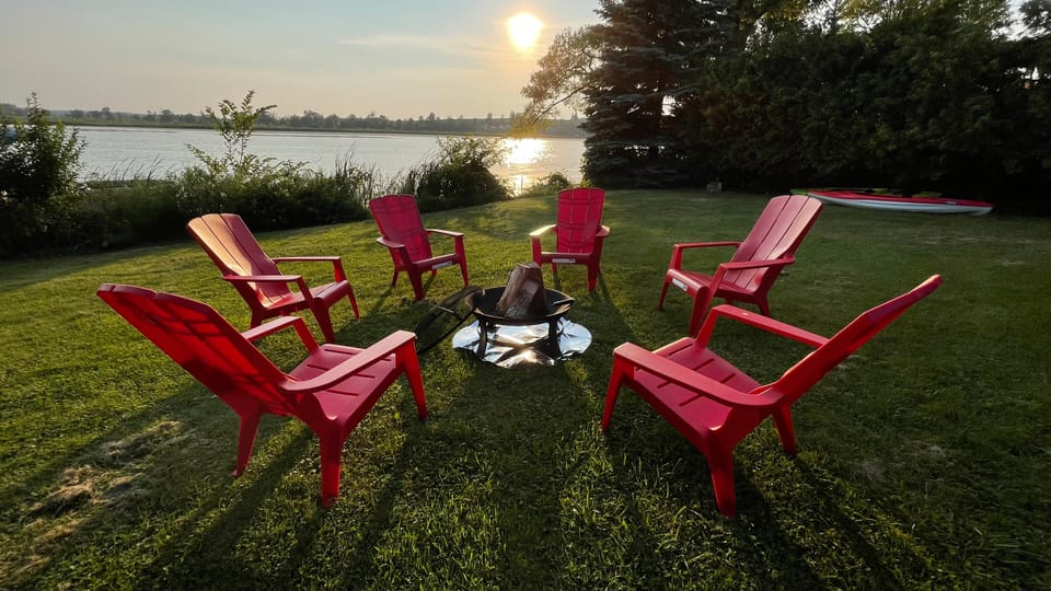Red Muskoka chairs circled around the fire pit as the sun drops