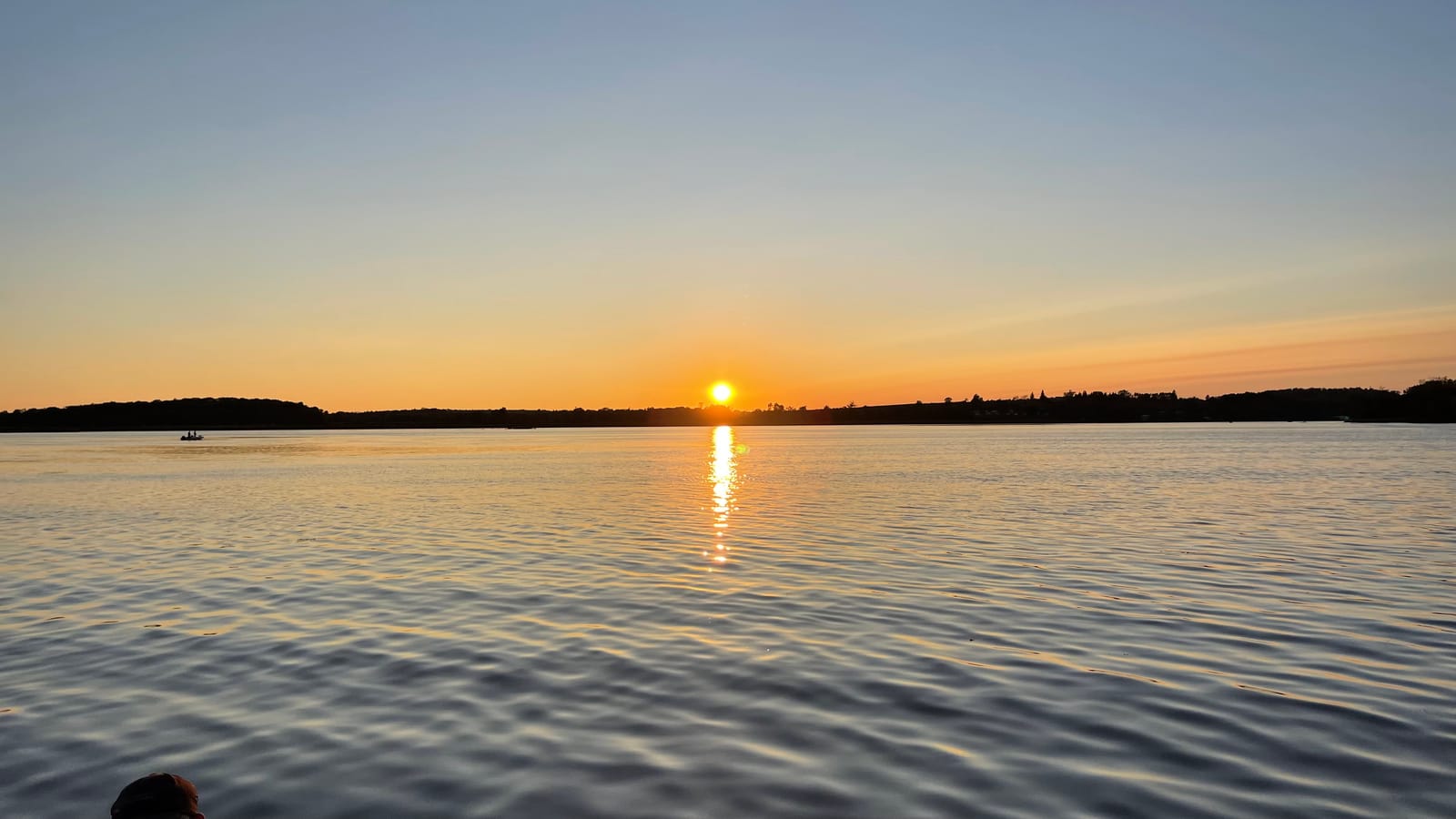 The sun touching the horizon across the water
